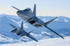 アラスカの雪山を背景に飛ぶ戦闘機F-22が美しい